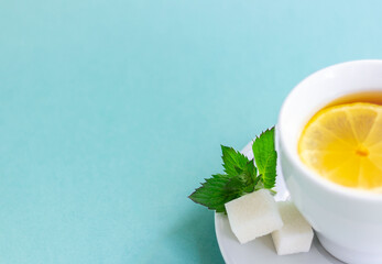 A Cup of tea with lemon and mint. Empty space for text. Isolated on a light blue background