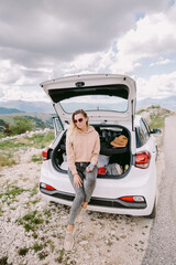 smiling woman relax in car driving in mountains. Tourist female on road trip by car to mountains countryside. Woman relax sitting in car with beautiful landscape view. Durmitor park in Montenegro.