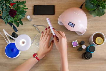 The girl processes nails with a nail file for manicure. Nail polish, tools for manicure. Ultraviolet lamp. Manicure at home.