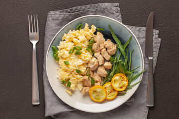 Diet lunch or dinner - egg scramble, chicken fillet, arugula leaves and slices of zucchini on a plate. Top view