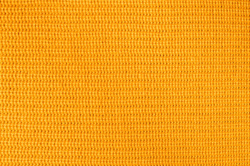 Wool background, top view. Orange knitted pattern of acrylic yarns, closeup.