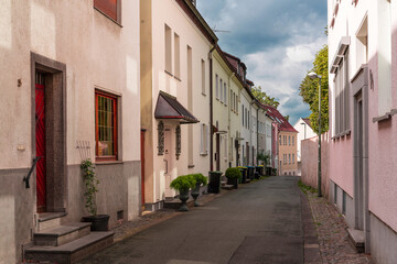 Fototapeta na wymiar Narrow city street with houses in warm pink tones and the cold gray sky.