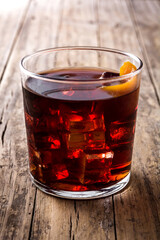 Boulevardier cocktail and orange zest in glass on wooden table
