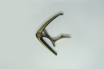Golden guitar capo selected on white background, close up.