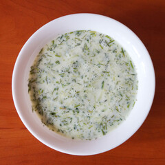 cucumber sour milk soup on a wooden table, top view.