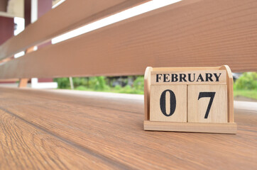 February 7, Number cube with wooden balcony background.