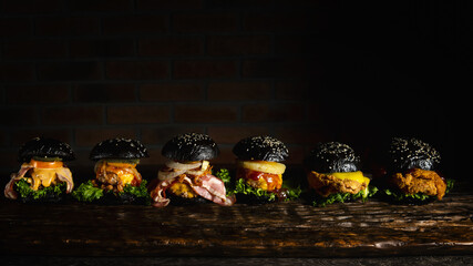 Front view of Mexican two pork burgers, two fried chicken burgers and two beef burgers served in black squid ink bun topped with pork bacon, tomato, pickled cucumber, onion and pine apple