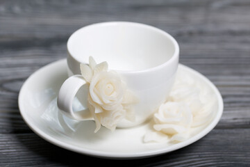 Handmade cup and saucer decorated with polymer clay roses. Jewelry made of white polymer clay.