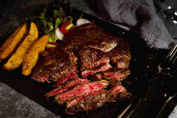 Australian rib eye steak with side vegetable lettuce, tomato, beat root and potato wedges topped with paprika with rose marry and black pepper background