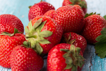 Fresh ripe perfect strawberry on blue wooden background. Fresh strawberry as texture background. Natural food backdrop with red berries. Strawberries sale in a food market in summer.