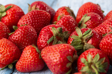 Fresh ripe perfect strawberry on wooden background. Fresh strawberry as texture background. Natural food backdrop with red berries. Strawberries sale in a food market in summer.