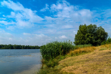 Picturesque lake on a sunny day. Light, white clouds in the blue sky.