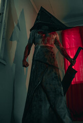 Cosplayer in the image of executioner stands in dark room with knife