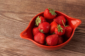 Fresh strawberries in a bowl on wooden table. Fresh nice strawberries. Strawberry field on fruit farm. Heap of Red strewberry on plate close up. Juice strawberry. Strawberry field on fruit farm.