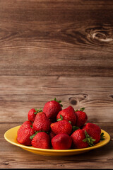 Fresh strawberries in plate on wooden table. Fresh nice strawberries. Strawberry field on fruit farm. Heap of Red strewberry on plate close up. Juice strawberry. Strawberry field on fruit farm.