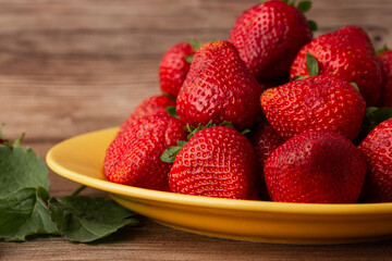 Fresh strawberries in plate on wooden table. Fresh nice strawberries. Strawberry field on fruit farm. Heap of Red strewberry on plate close up. Juice strawberry. Strawberry field on fruit farm.