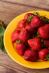 Fresh strawberries in plate on wooden table. Fresh nice strawberries. Strawberry field on fruit farm. Heap of Red strewberry on plate close up. Juice strawberry. Strawberry field on fruit farm.
