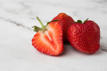 Fresh ripe perfect pieces strawberry on white marble background. Fresh strawberry isolated. Natural food backdrop with red berries. Strawberries sale in a food market in summer.