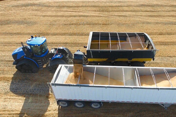 loading grain harvester into haulage track farming agriculture