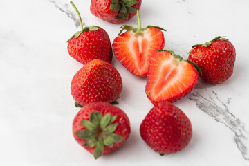 Fresh ripe perfect pieces strawberry on white marble background. Fresh strawberry isolated. Natural food backdrop with red berries. Strawberries sale in a food market in summer.