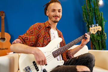 Young caucasian man with dreadlocks playing electric guitar in his room