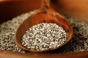 Chia seeds in a bowl with wooden spoon