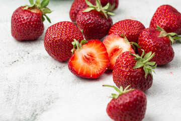 Fresh ripe perfect pieces strawberry on white marble background. Fresh strawberry as texture background. Natural food backdrop with red berries. Strawberries sale in a food market in summer.