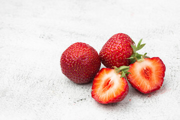 Fresh ripe perfect pieces strawberry on white marble background. Fresh strawberry as texture background. Natural food backdrop with red berries. Strawberries sale in a food market in summer.