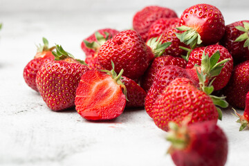 Fresh ripe perfect pieces strawberry on white marble background. Fresh strawberry as texture background. Natural food backdrop with red berries. Strawberries sale in a food market in summer.