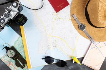 Tourist planning with map. Various accessories traveler on table, black background. Top view