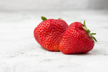 Fresh ripe perfect strawberry on white marble background. Two fresh strawberry isolated. Natural food backdrop with red berries. Strawberries sale in a food market in summer.