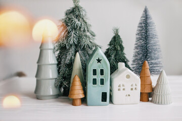 Christmas little houses and trees with golden lights bokeh on white background. Festive modern...