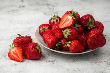 Fresh strawberries in plate on marble white table. Fresh nice strawberries. Strawberry field on fruit farm. Heap of Red strewberry on plate close up. Juice strawberry. Strawberry field on fruit farm.