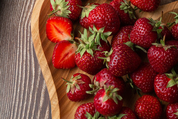 Fresh strawberries in a wooden plate on wooden table. Fresh nice strawberries. Strawberry field on fruit farm. Heap of Red strewberry on plate. Juice strawberry. Strawberry field on fruit farm.