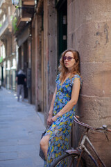 Fototapeta premium Beautiful girl with a bicycle on the street of an ancient city.