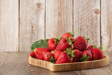 Fresh strawberries in a wooden plate on wooden table. Fresh nice strawberries. Strawberry field on fruit farm. Heap of Red strewberry on plate. Juice strawberry. Strawberry field on fruit farm.