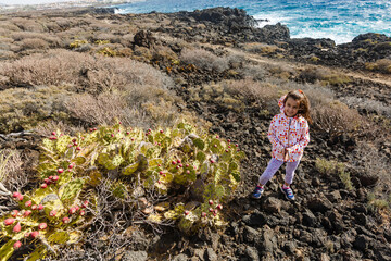 Fototapeta premium little girl stands near a cactus on the island of tenerife
