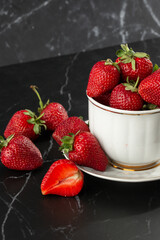Fresh strawberries in a white cup on marble black table. Fresh nice strawberries. Strawberry field on fruit farm. Heap of Red strewberry on plate. Juice strawberry. Strawberry field on fruit farm.