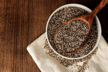 Chia seeds in a bowl with wooden spoon