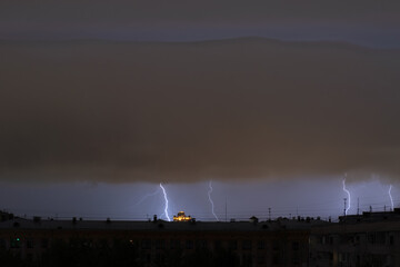 Lightning shines in the sky over the night city. Storm over city. 