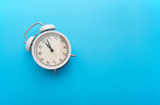 White iron alarm clock on blue background, top view, concept picture