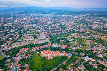 Aerial view of medieval castle Palanok, Mukachevo (Munkacs), Transcarpathia (Zakarpattia), Ukraine. Summer landscape with old architecture, green trees and town, outdoor travel background