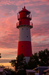 A small and beautiful lighthouse in the evening dawn sunset with pink clouds and bright light in Falsh&ouml;ft, Germany
