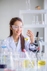 Young Asian scientist woman lab technical service holding flask with lab glassware and test tubes in chemical laboratory background, science laboratory research and development concept