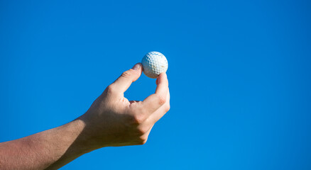 Golf ball held in hand against the blue sky golf concept
