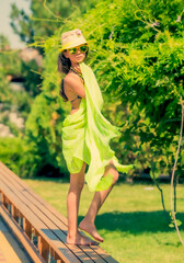 Model looking Girl standing in a swimsuit on the background of green grass and forest.