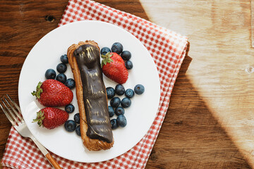 Chocolate eclair with berries in white plate