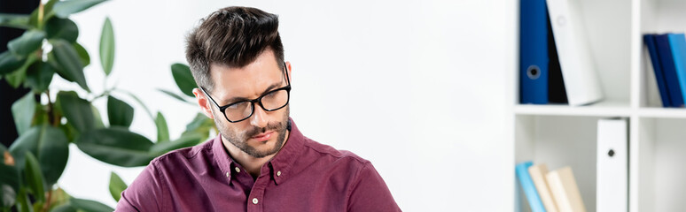 Obraz premium website header of serious, thoughtful businessman working in office near potted plant