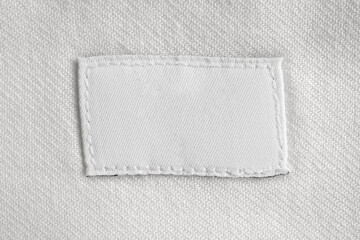 White blank laundry care clothes label on cotton shirt background