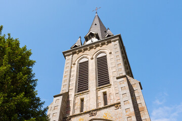 Fototapeta na wymiar Beautiful close up of Notre-Dame-de-l'Assomption church tower (La Lande Patry, Normandy, France). Sunny day in the north of France. Stone christian church.